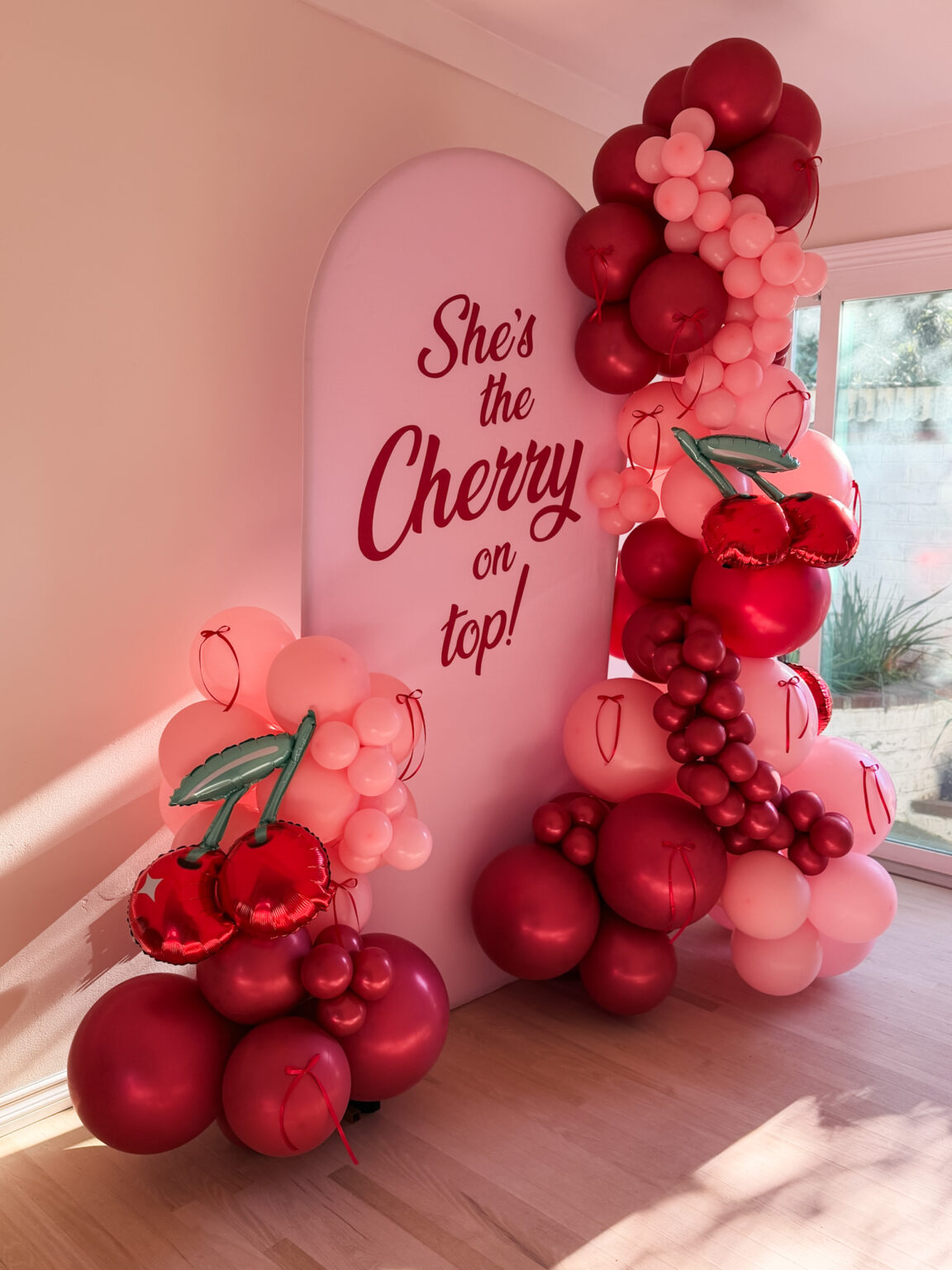 "She's the Cherry on Top" arch sign wrapped in red and pink cherry-style balloons
