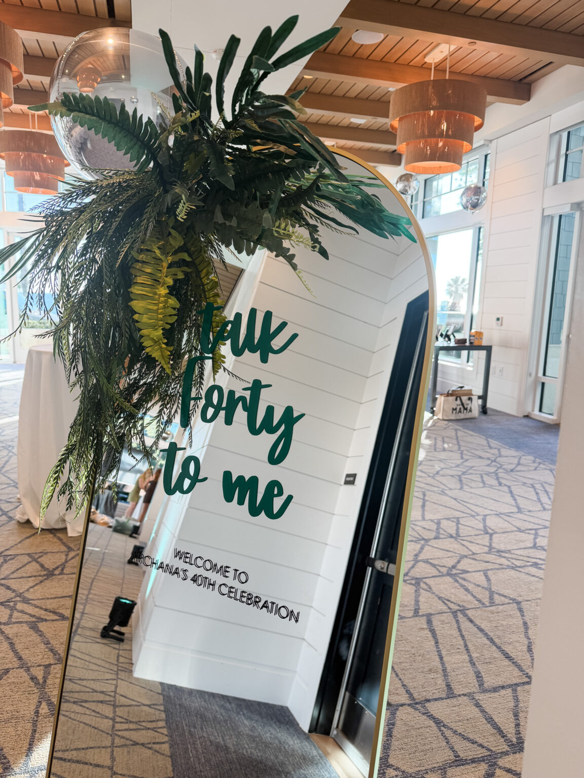 Custom 40th birthday welcome sign topped with tropical palm leaves at the entrance of a waterfront venue