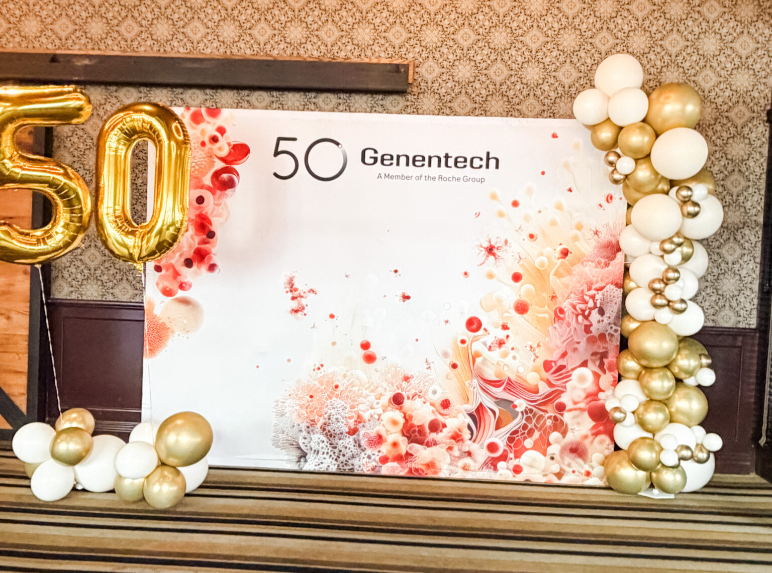 Corporate 50th anniversary backdrop for Genentech framed by gold, white and champagne balloons with gold 50 number balloons