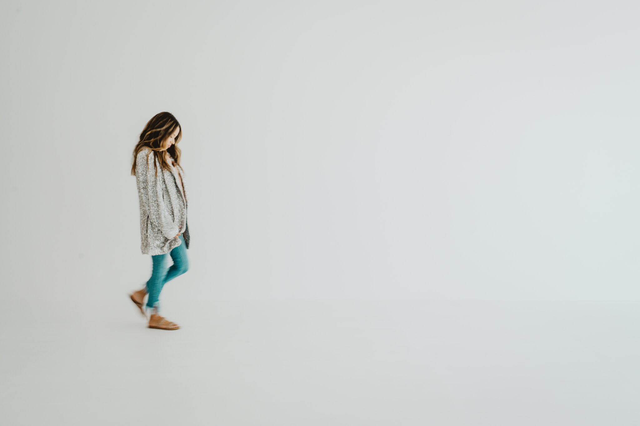 Andrea Laparra of Wee Gather in a silver blazer walking across a bright, empty white room